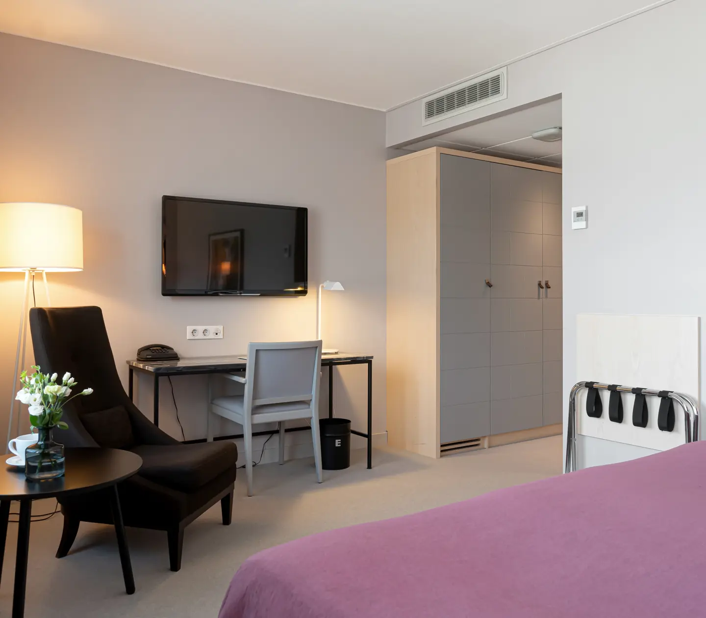 Hotellrum med garderob, skrivbord och fåtölj