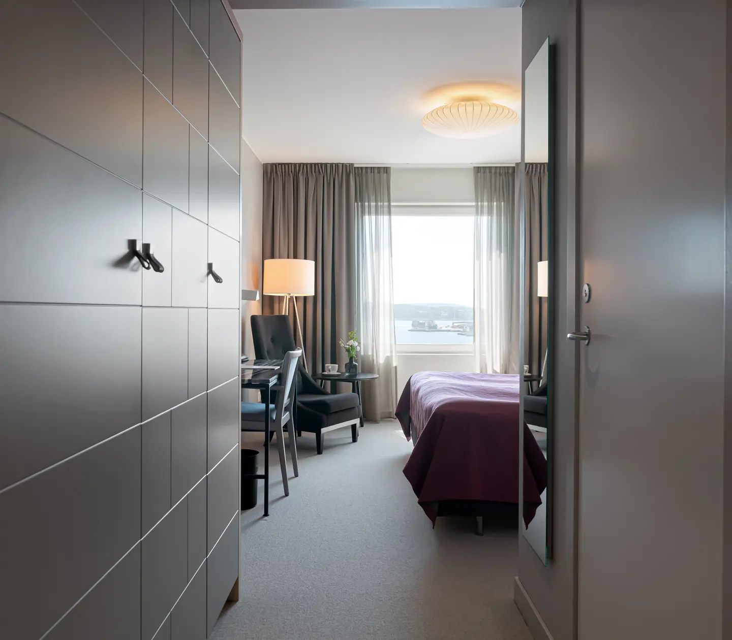 Hotellrum med garderob, fåtölj och fönster