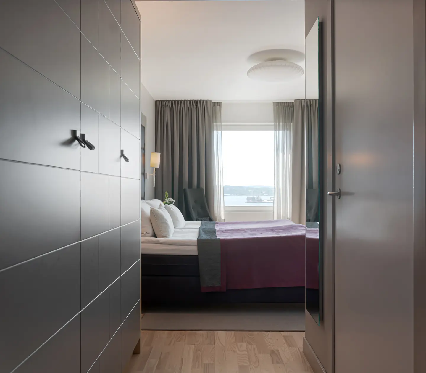 Hotellrum med garderob, dubbelsäng och fönster