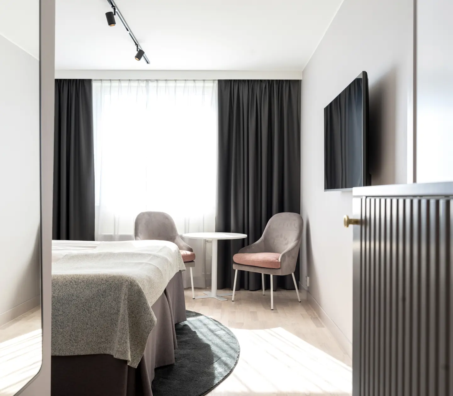 Hotellrum med säng, fåtöljer och tv