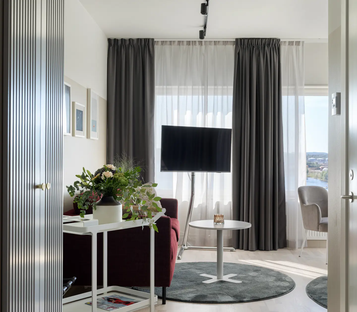Hotellrum med garderob, soffa, tv och fönster