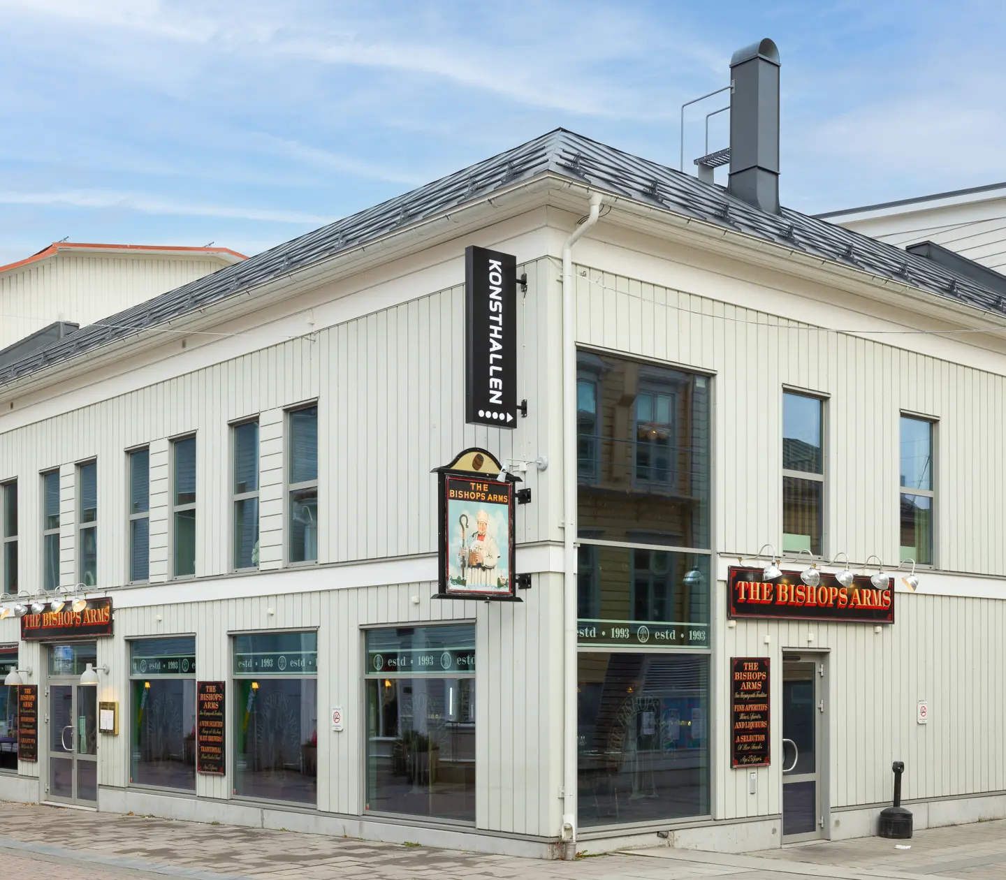 Vita fasaden av Hotel Bishops Arms med skyltar och stora fönster