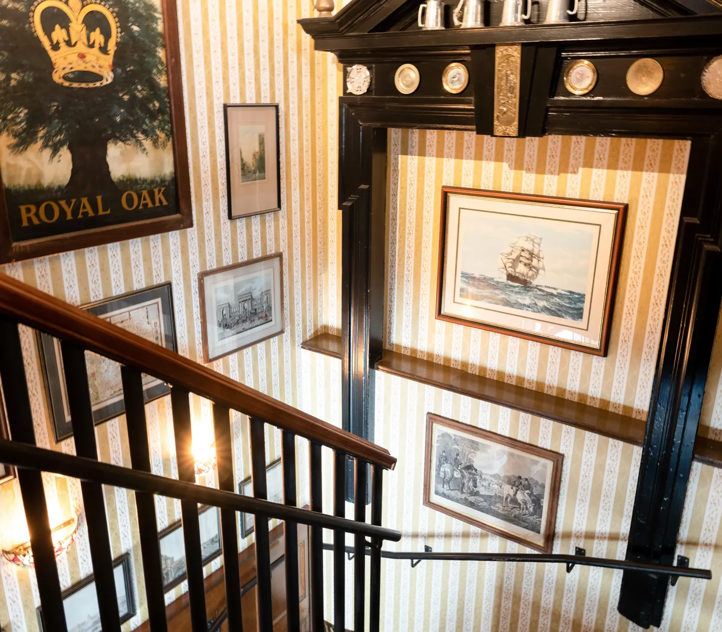 Hotellmiljö med trapp, randiga tapeter och många tavlor