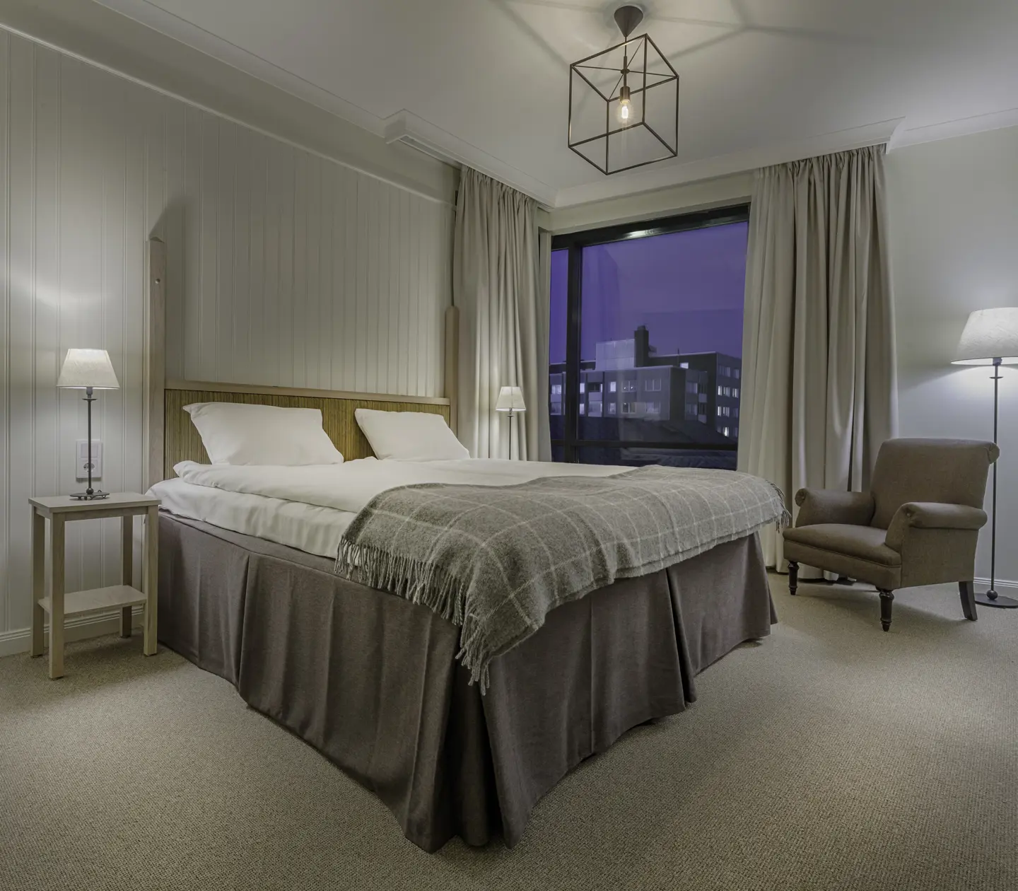 Mysigt hotellrum med säng, fåtölj och fönster