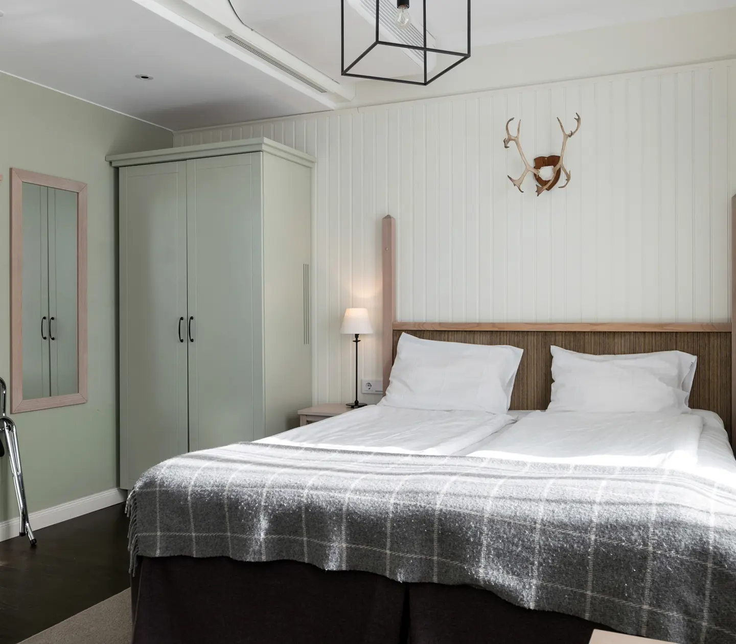 Mysigt hotellrum med säng, garderob och djurhorn på väggen