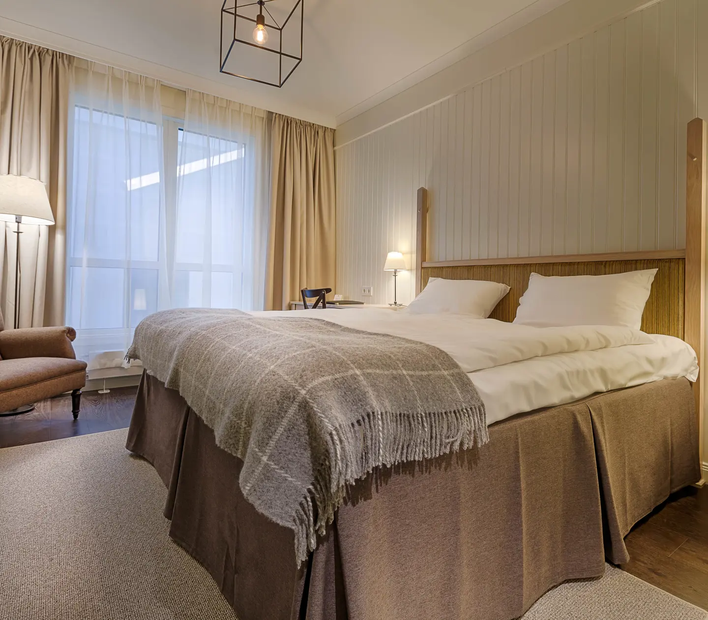 Mysigt hotellrum med säng, fåtölj och fönster