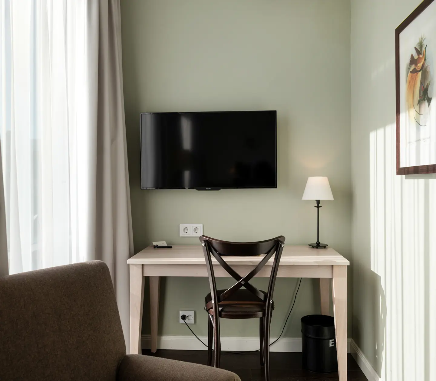 Mysigt hotellrum med skrivbord, fåtölj och tv