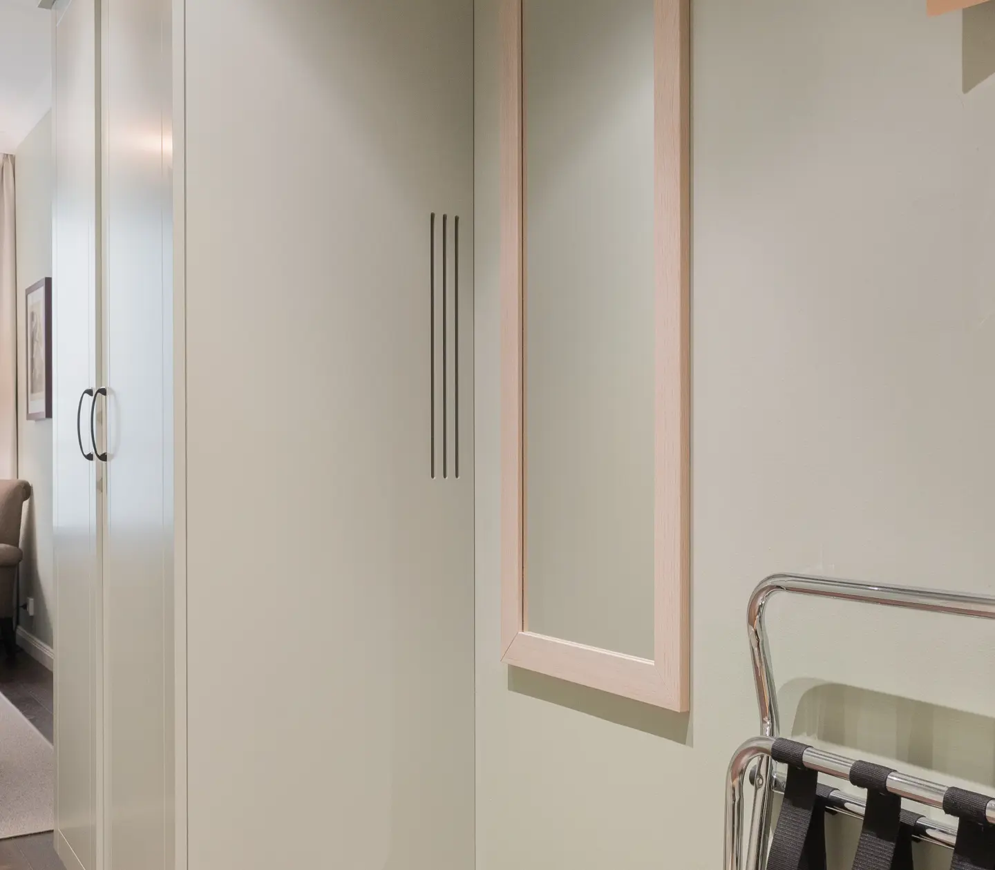 Hotellrum med klädhängare, spegel och garderob