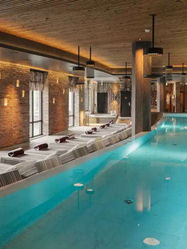 Spamiljö med stor pool, många solsängar och stora fönster