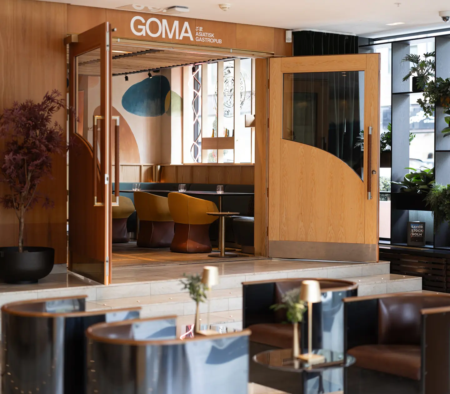 Ingången till den asiatiska gastropuben GOMA med moderna möbler och växtinredning.