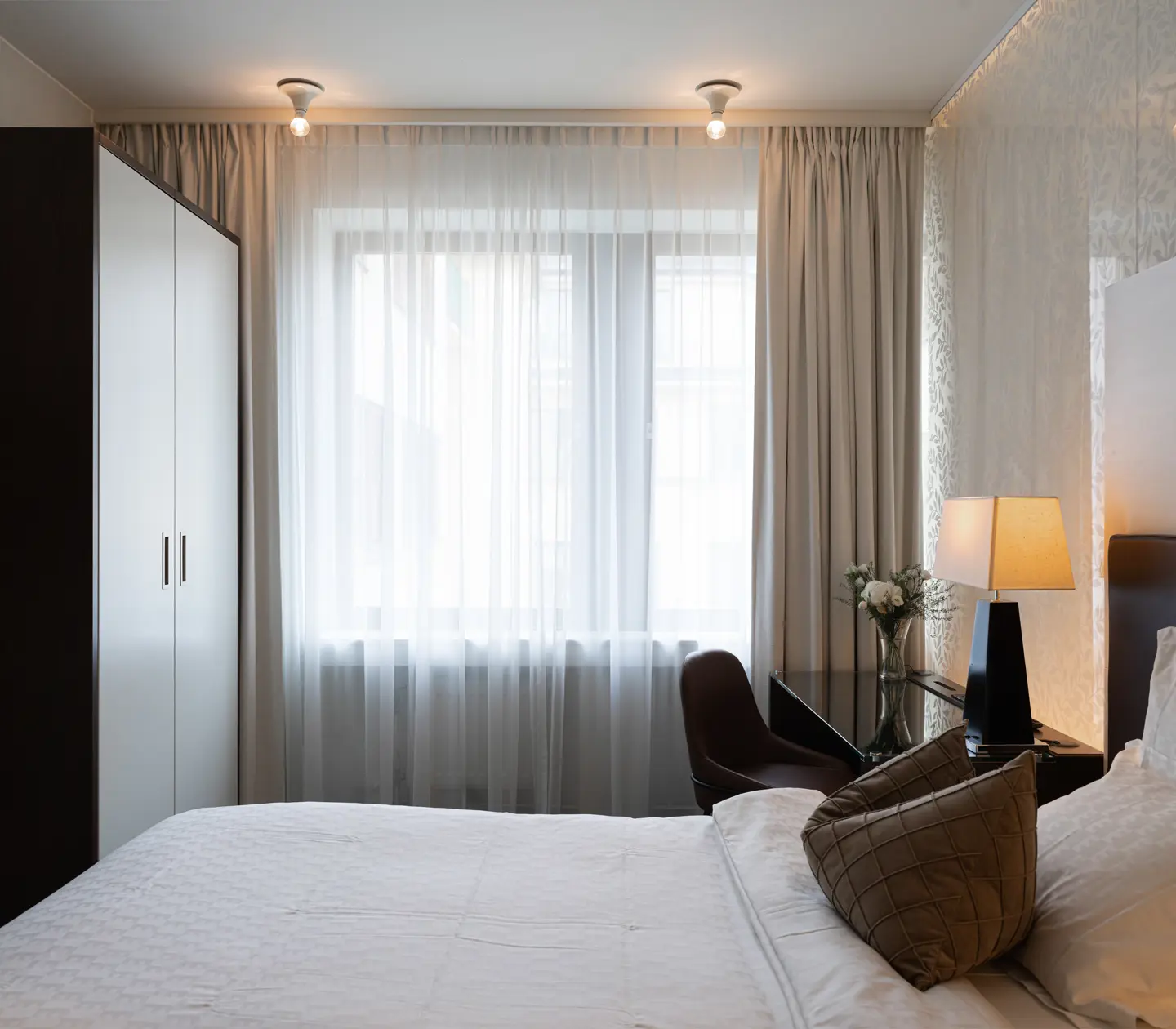 Ljust hotellrum med säng, skrivbord och fönster