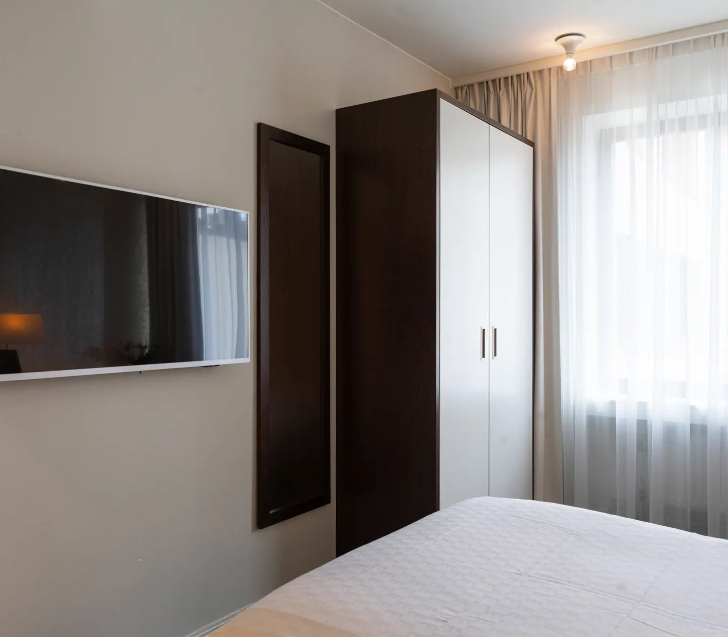 Ljust hotellrum med säng, tv och fönster