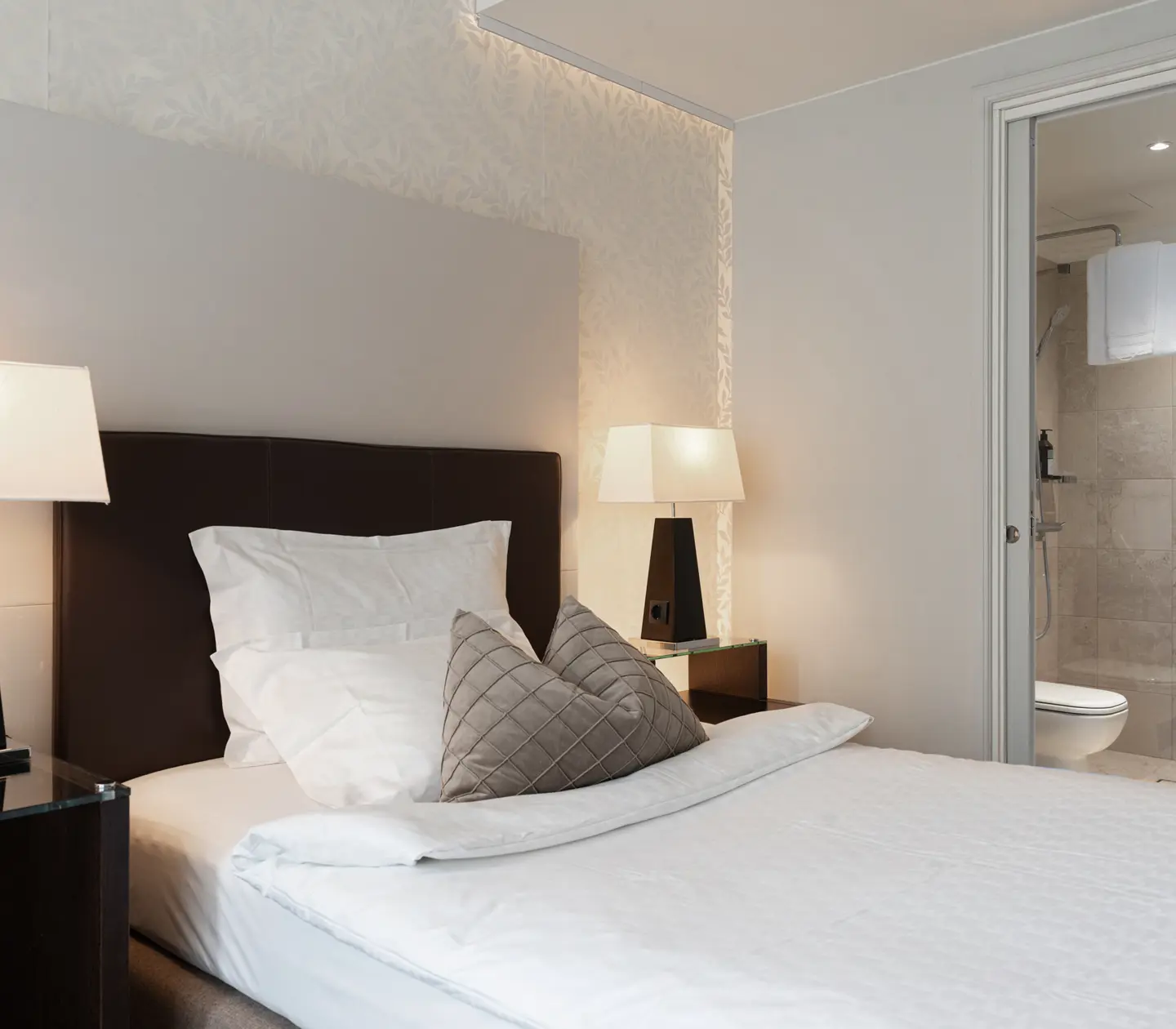 Ljust hotellrum med säng, skrivbord och badrum