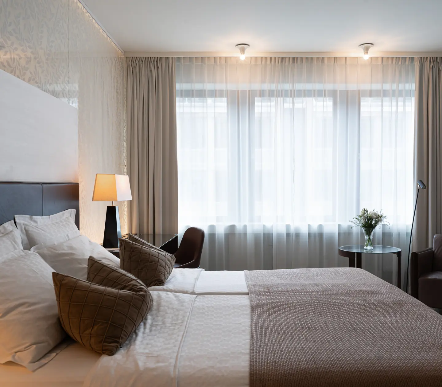 Ljust hotellrum med säng, skrivbord och fönster