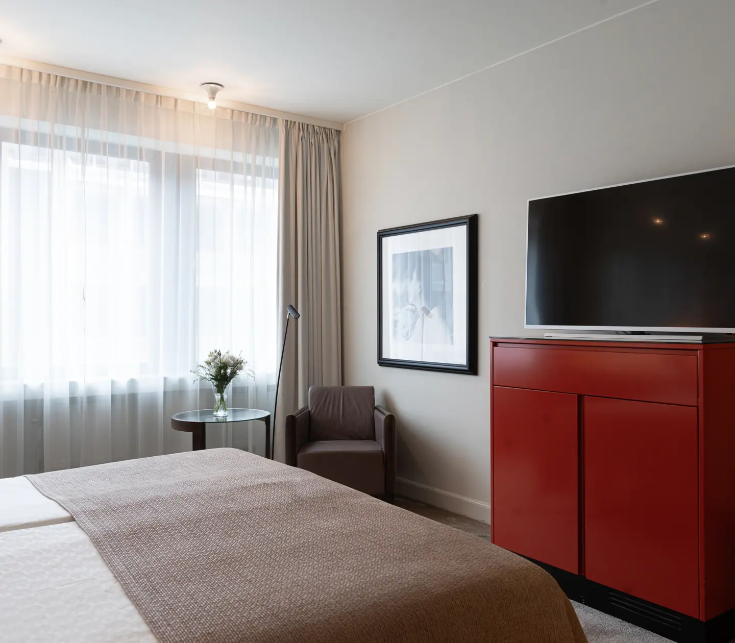 Ljust hotellrum med säng, skrivbord och fönster