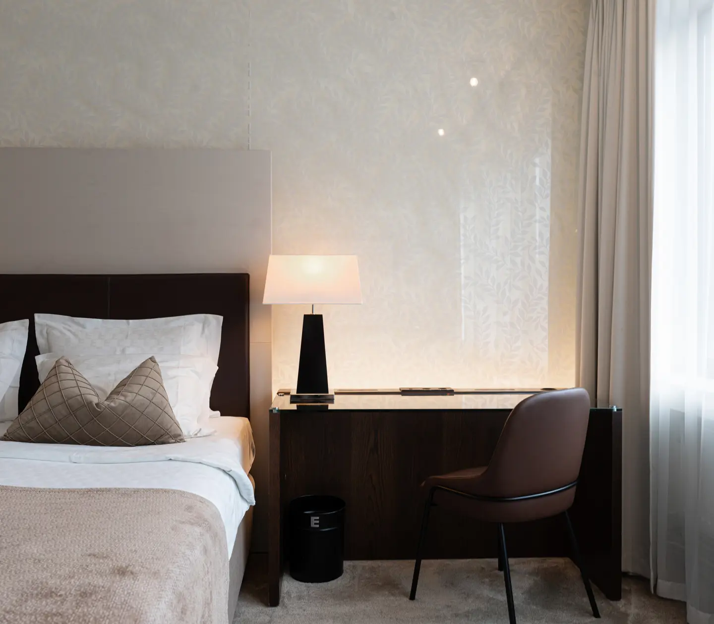Ljust hotellrum med säng, skrivbord och fönster