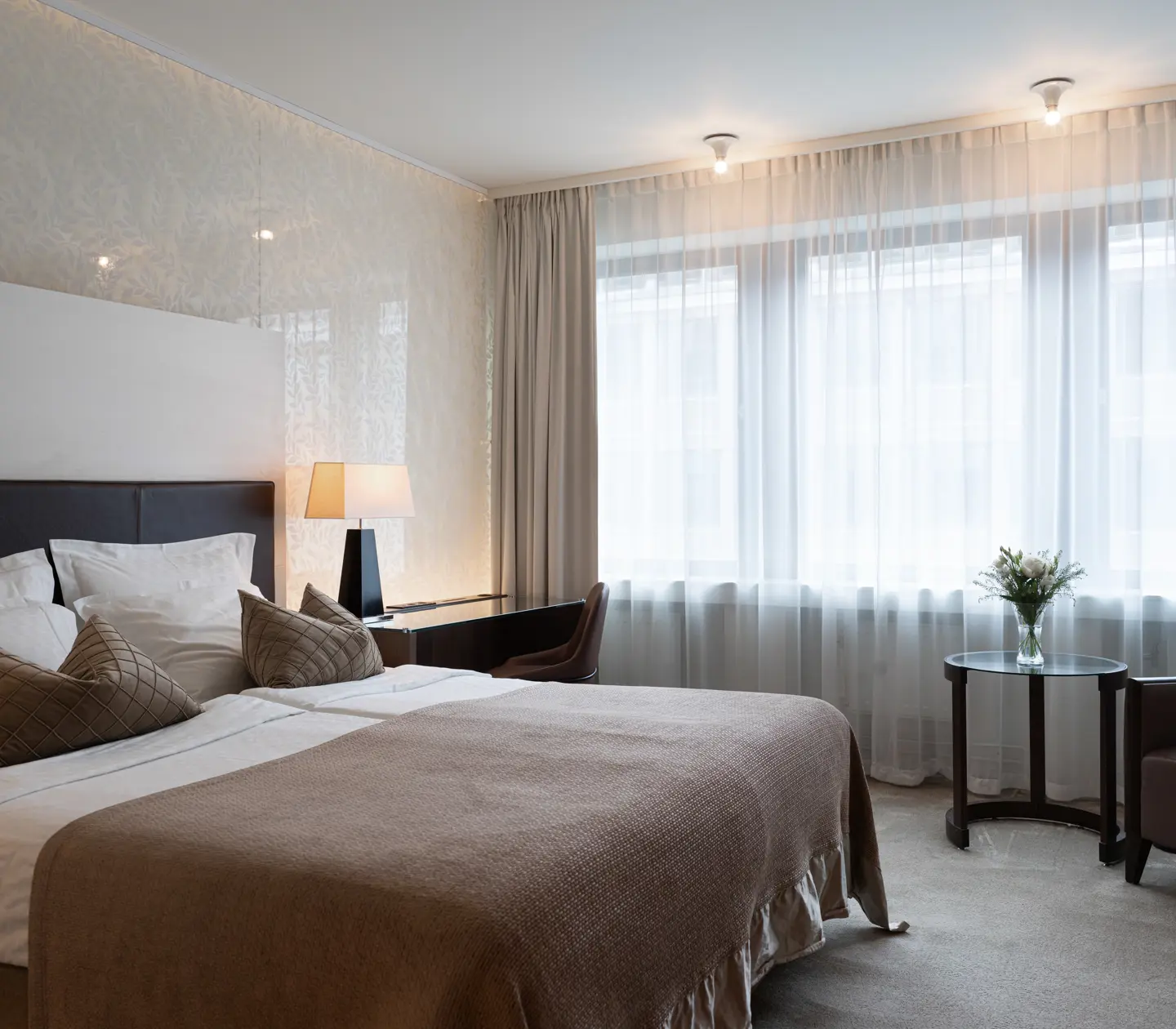 Ljust hotellrum med säng, skrivbord och fönster