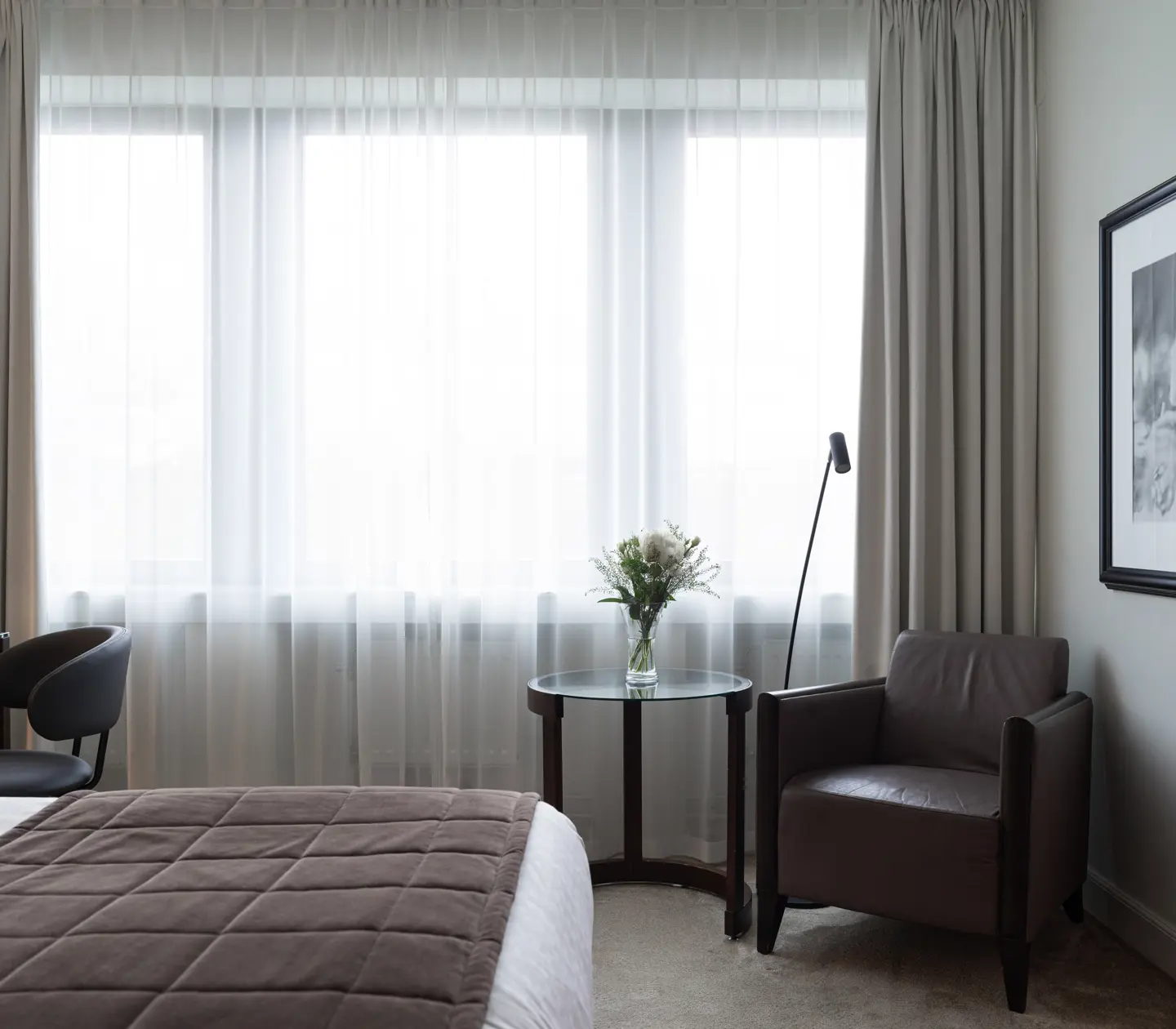 Ljust hotellrum med säng, skrivbord och sänglampa