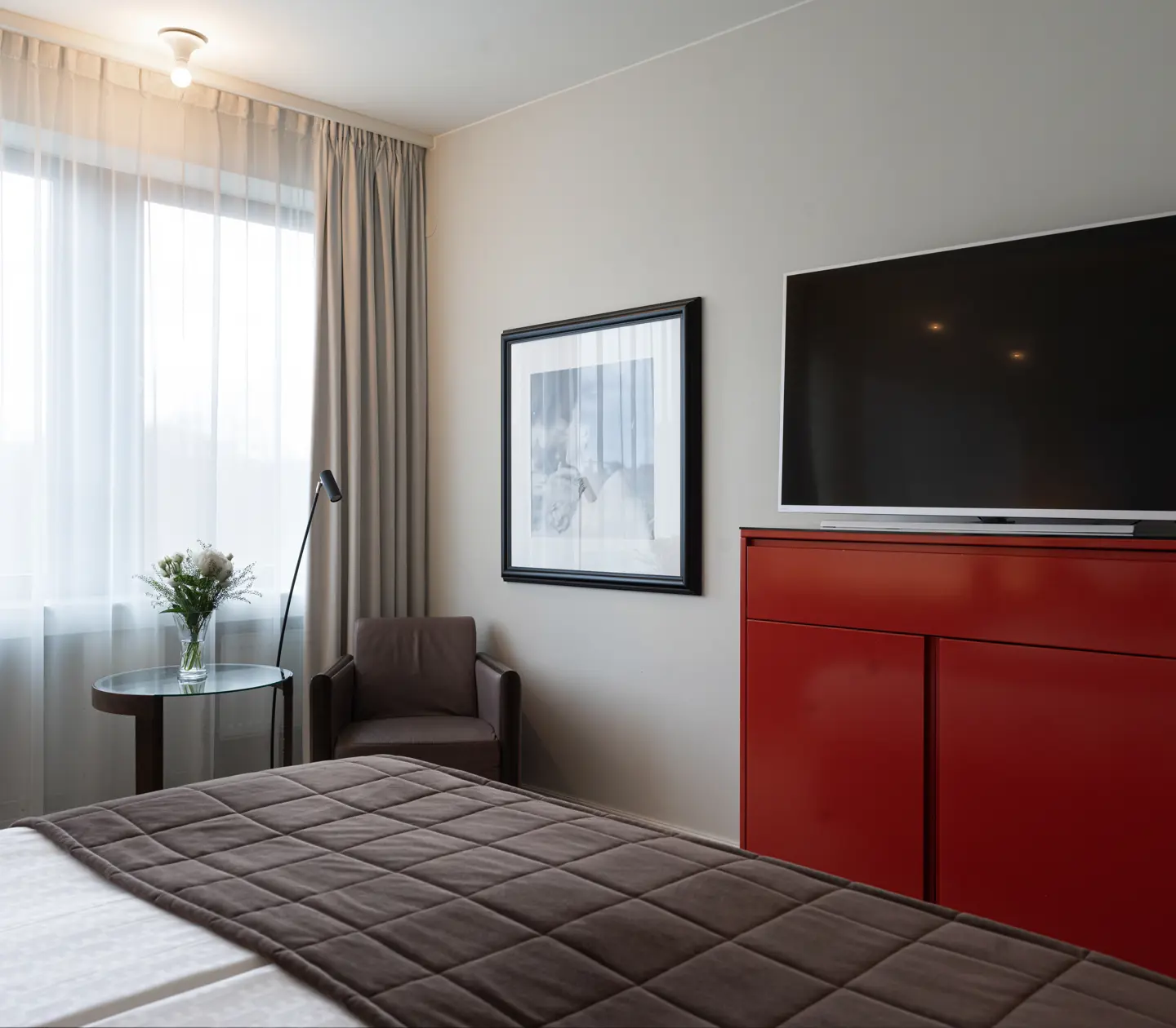 Ljust hotellrum med säng, tv och tv-bänk