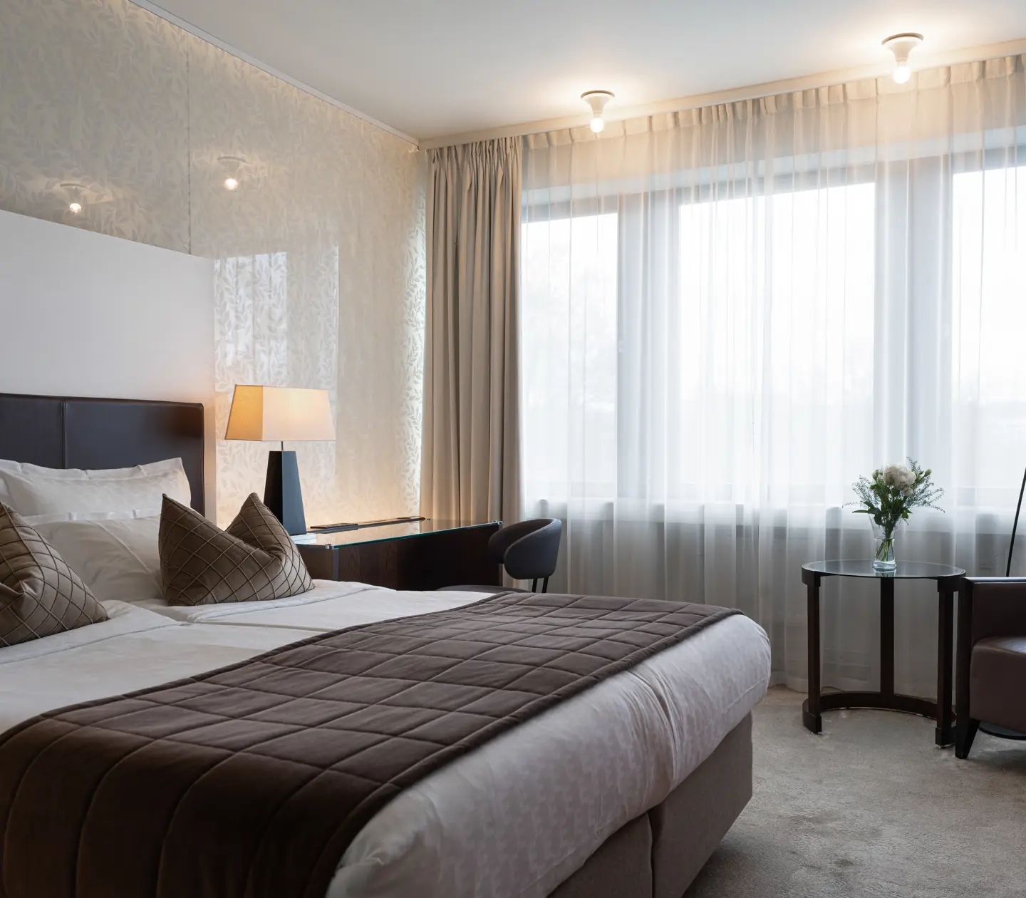 Ljust hotellrum med säng, skrivbord och fönster