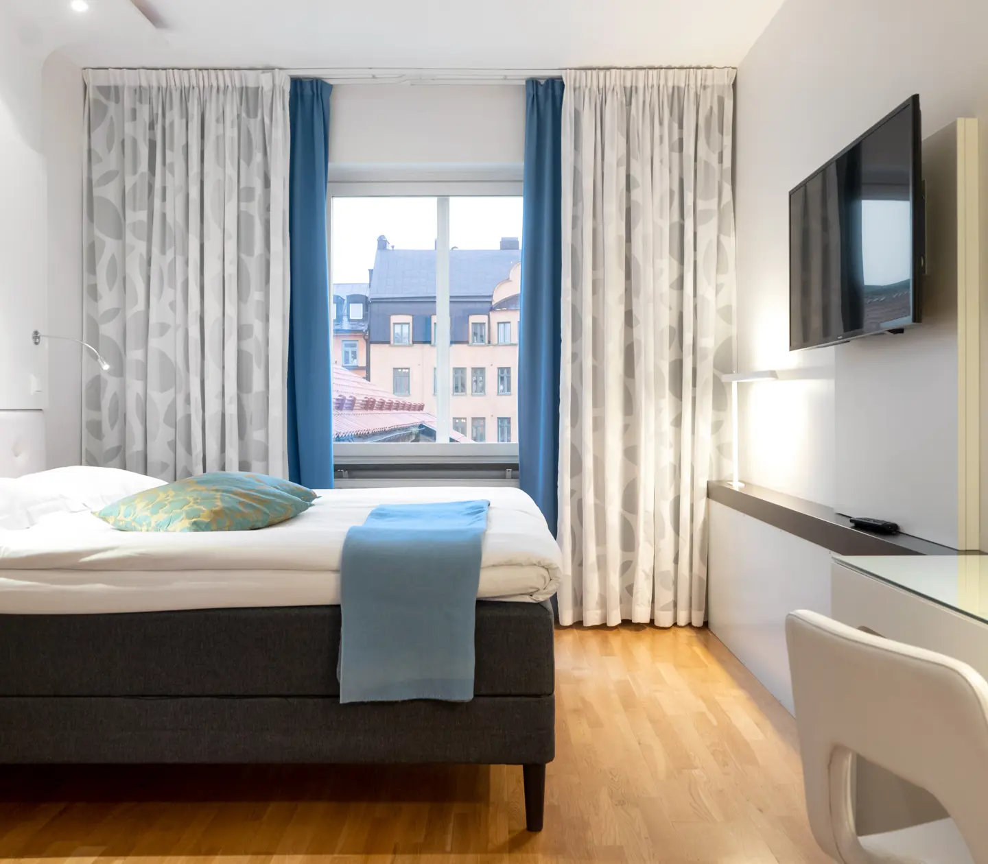 Ljust hotellrum med soffa, tv och fönster