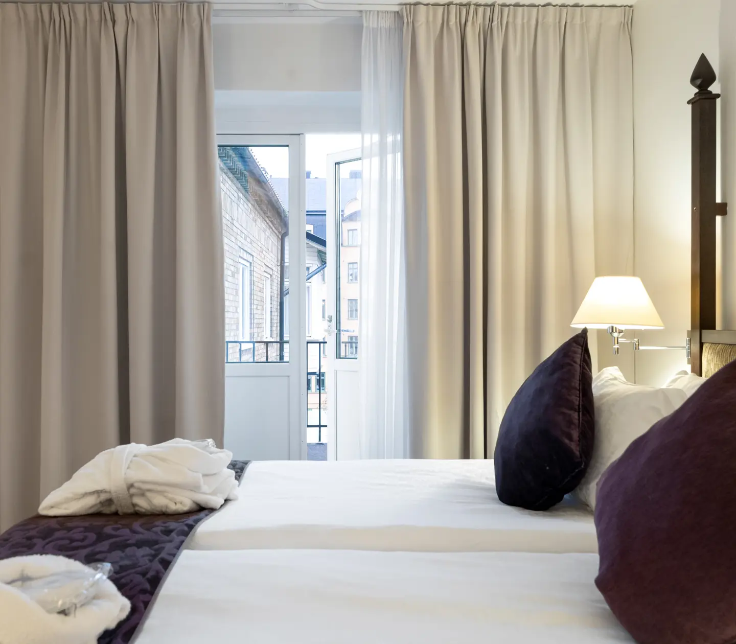 Hotellrum med säng, morgonrockar och öppen balkongdörr