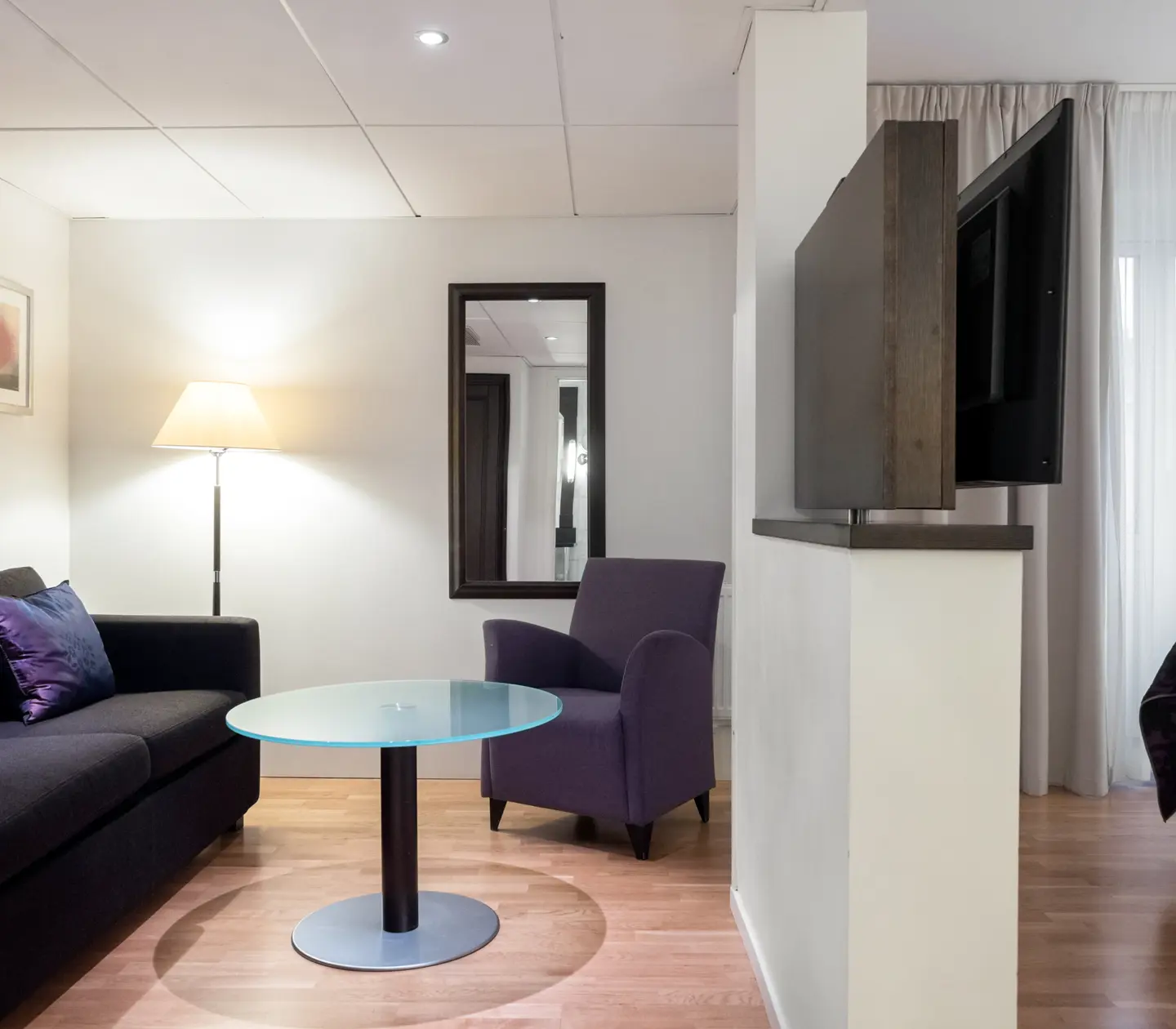 Ljus svit med soffgrupp, tv och spegel