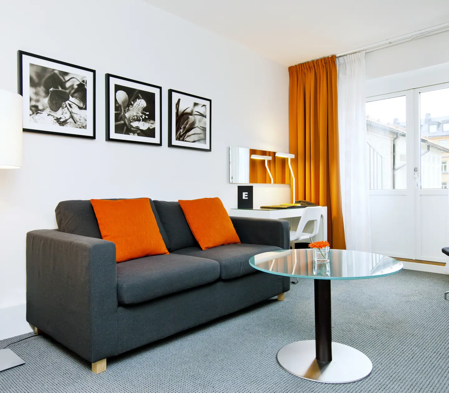 Ljus svit med säng, orange textilier och skrivbord