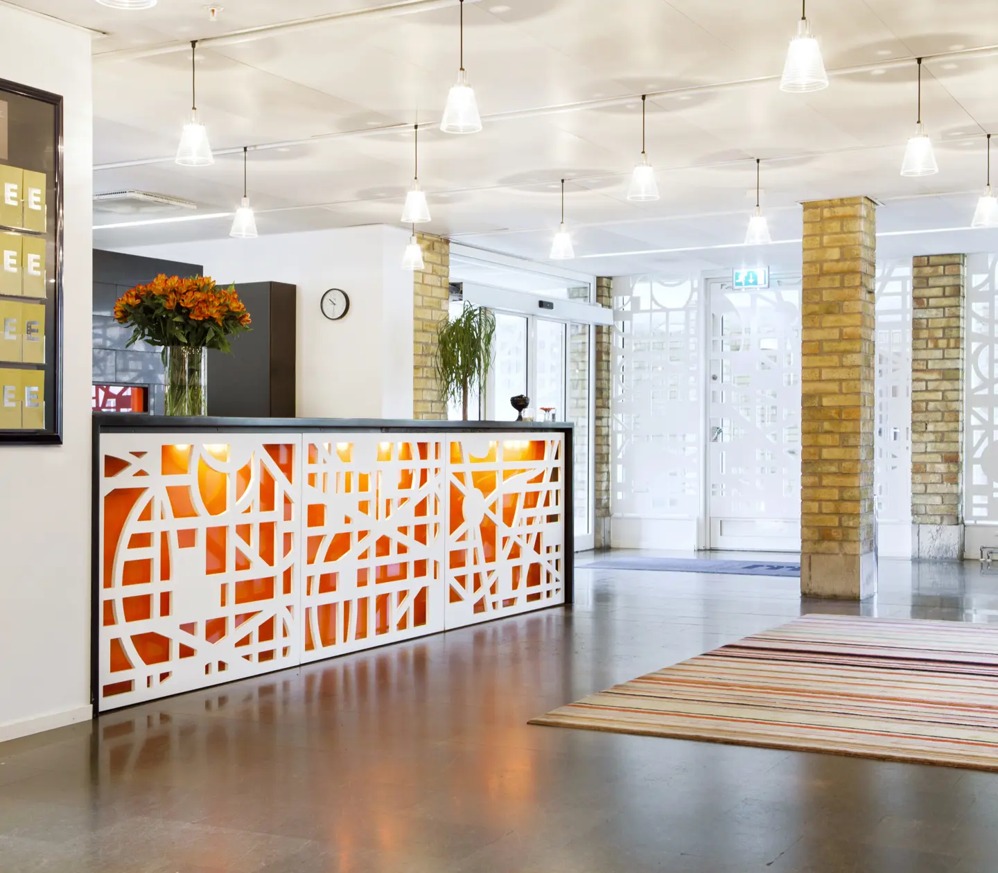 Hotellobby med receptionsdisk, fönster och taklampor