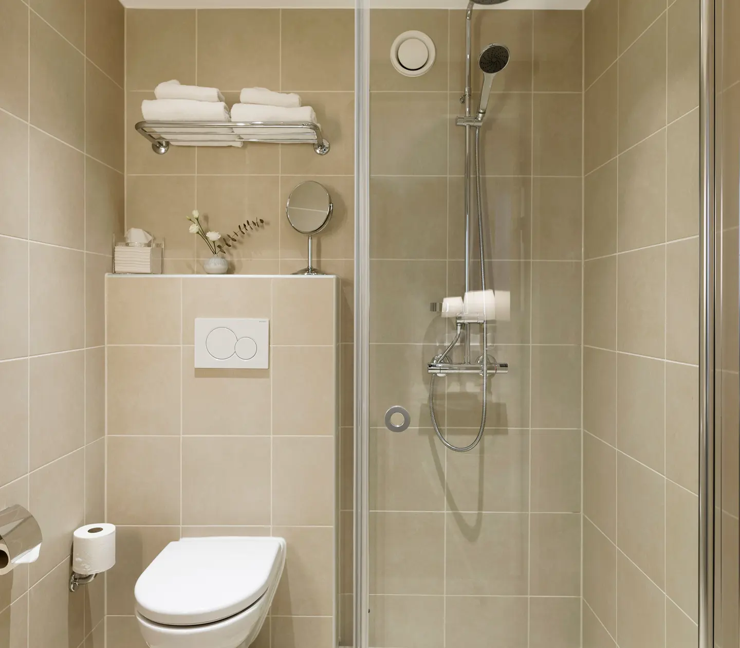 Beige badrum med toalett, handfat och dusch