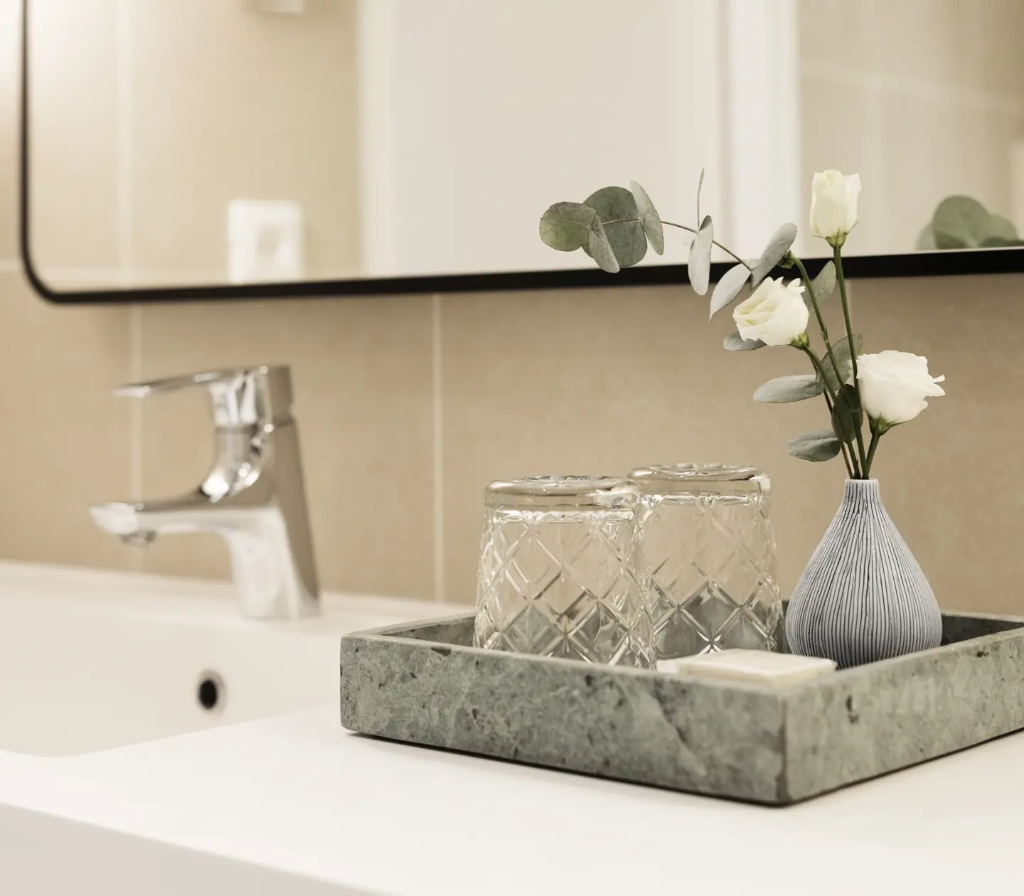 Beige badrum med handfat och marmorbricka med glas och blomma