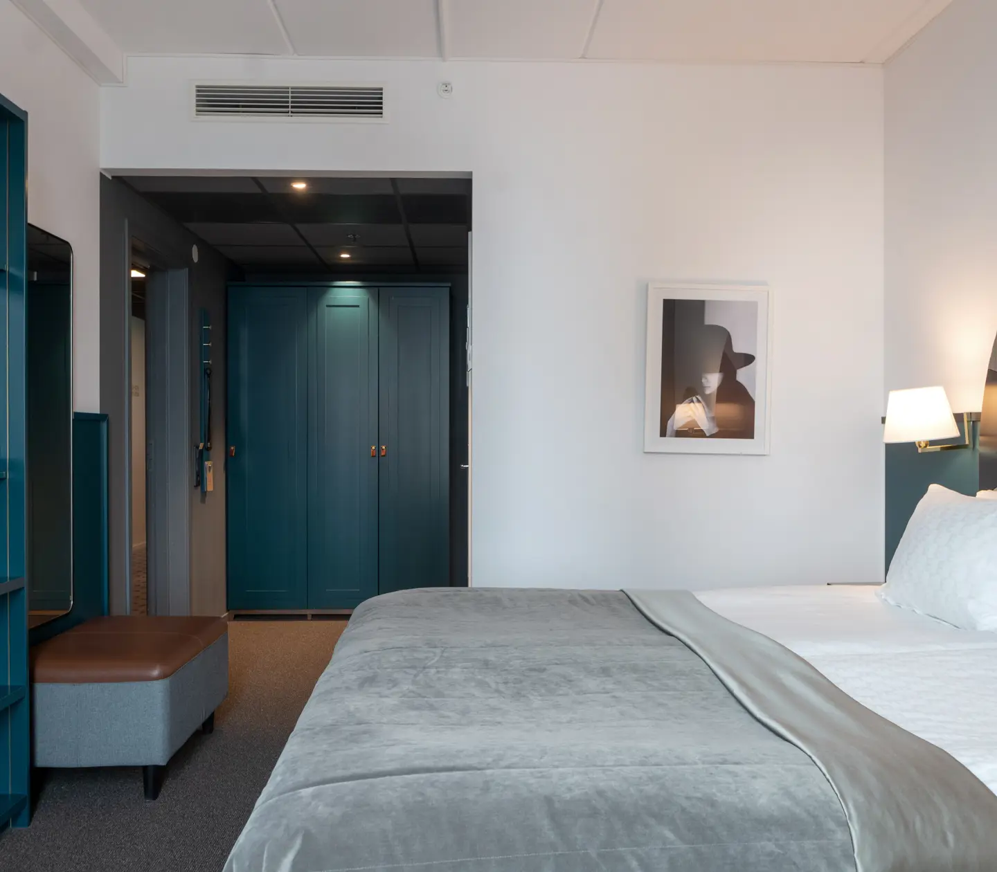 Ljust hotellrum med säng, garderob och bokhylla