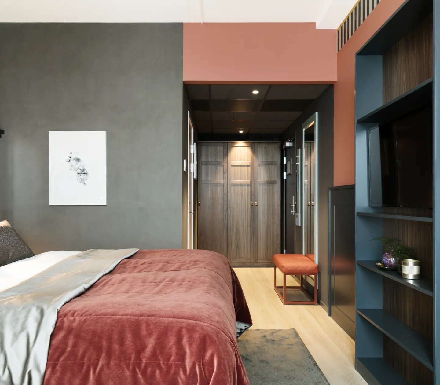 Mysigt hotellrum med säng, bokhylla och garderob