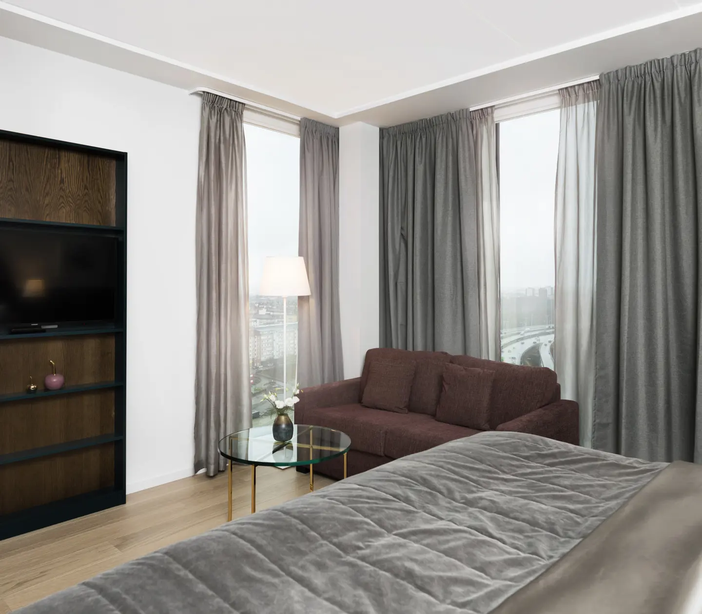 Ljust hotellrum med bokhylla, soffa och stora fönster