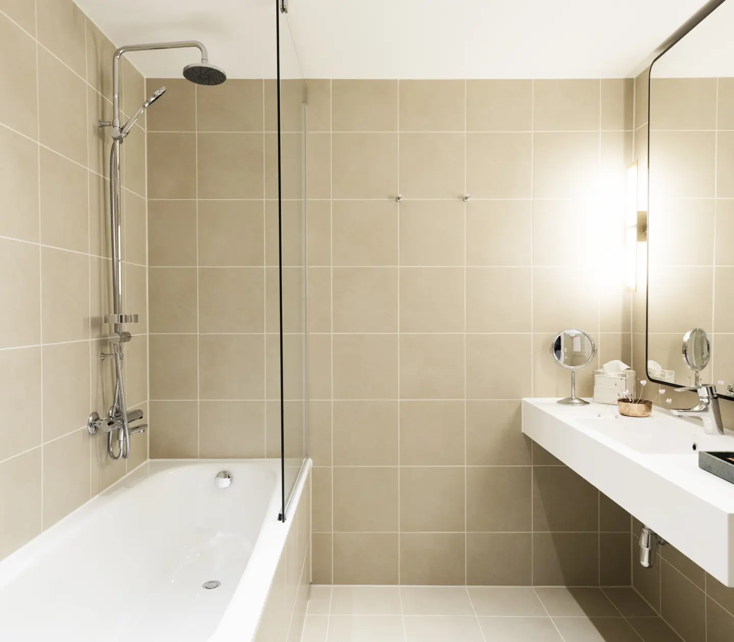 Beige badrum med badkar, handfat och spegel
