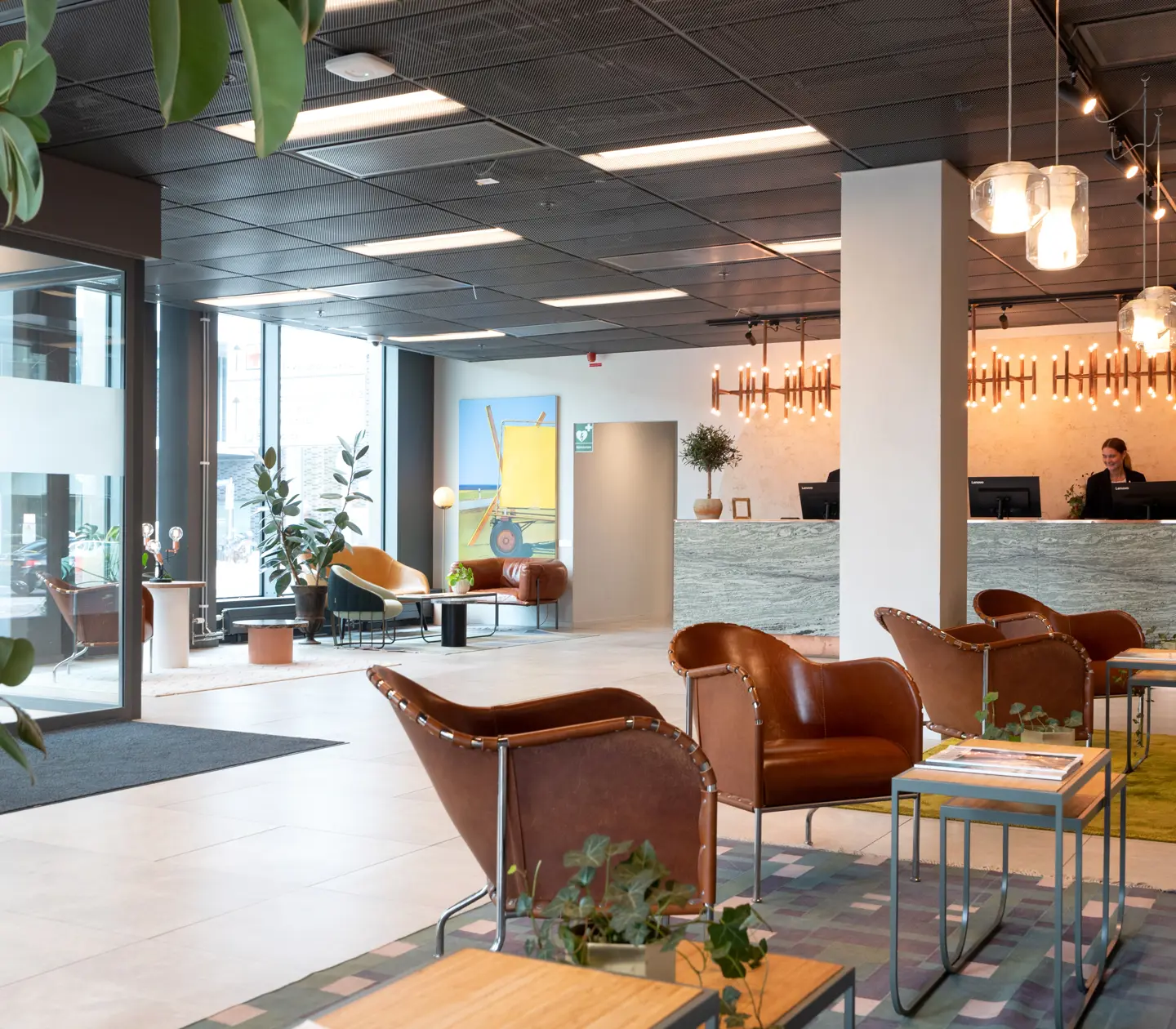 Hotellobby med receptionsdisk, fönster och loungemöbler