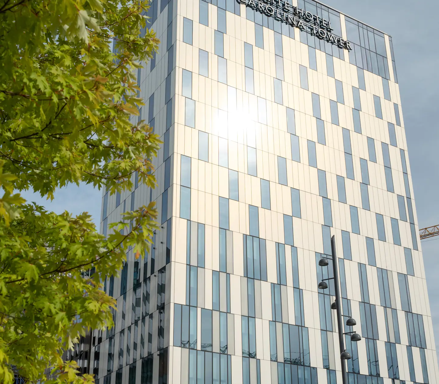Den svartvita höga fasaden av Elite Hotel Carolina Tower med träd framför