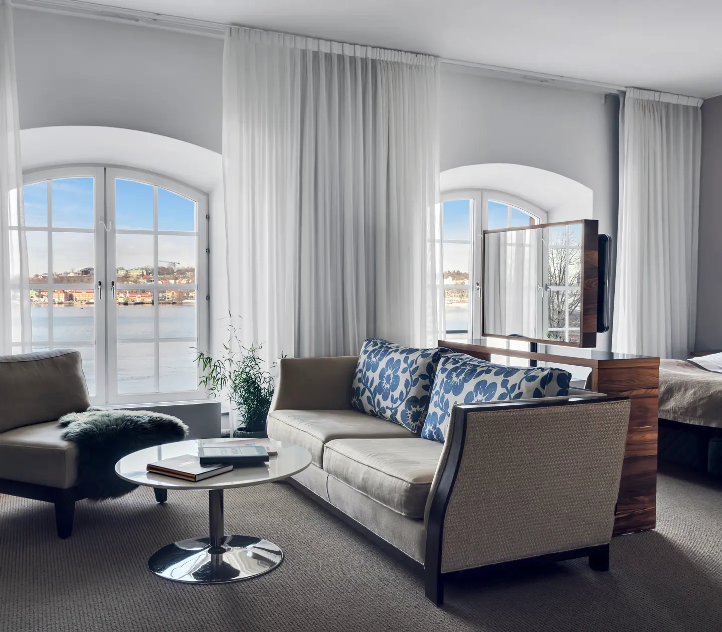 Ljust hotellrum med säng, soffgrupp och stora fönster med havsutsikt