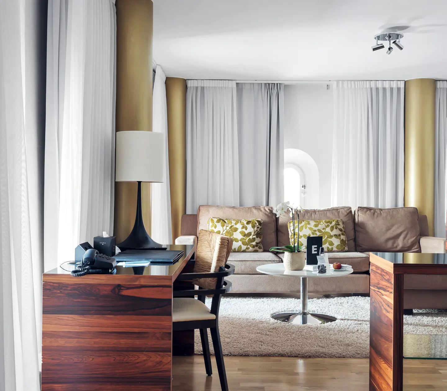 Ljus svit med soffgrupp, skrivbord och gardiner längs väggarna