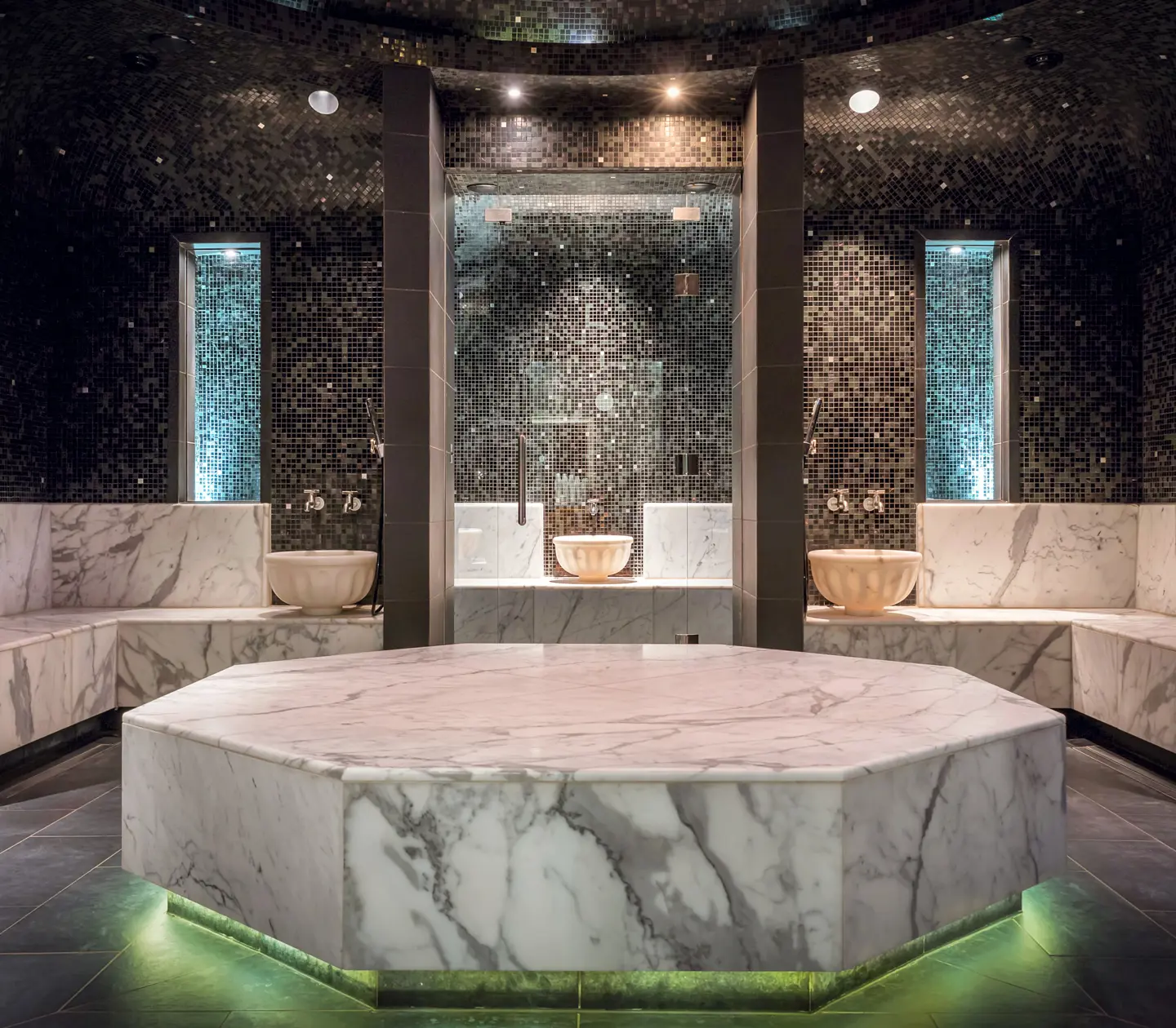 Spamiljö med turkisk hamam med svart kakel på väggarna och vit marmor