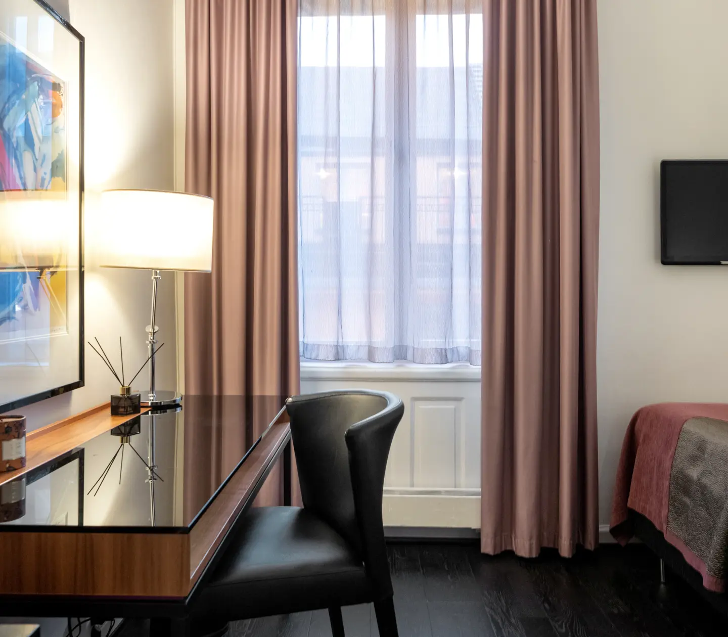 Hotellrum med skrivbord, tavla, enkelsäng, tv och fönster