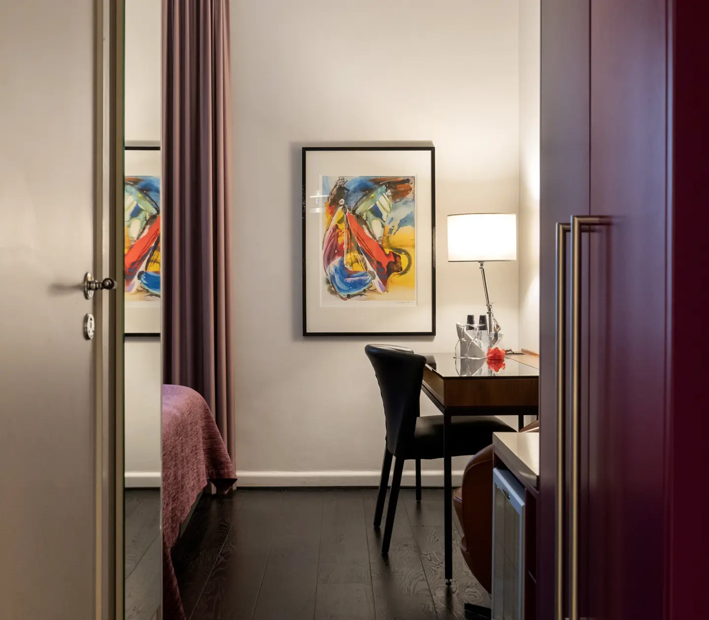 Hotellrum med spegel, tavla, garderob och skrivbord