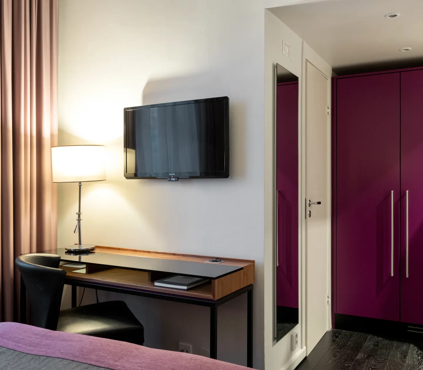Hotellrum med skrivbord, tv, spegel och garderob