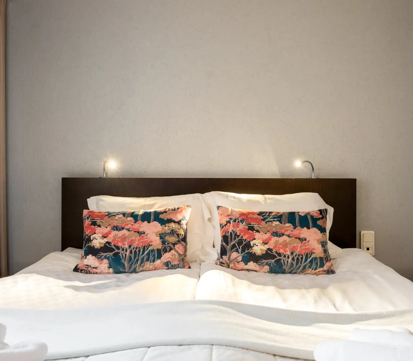Hotellrum med dubbelsäng med blommiga kuddar och lampor