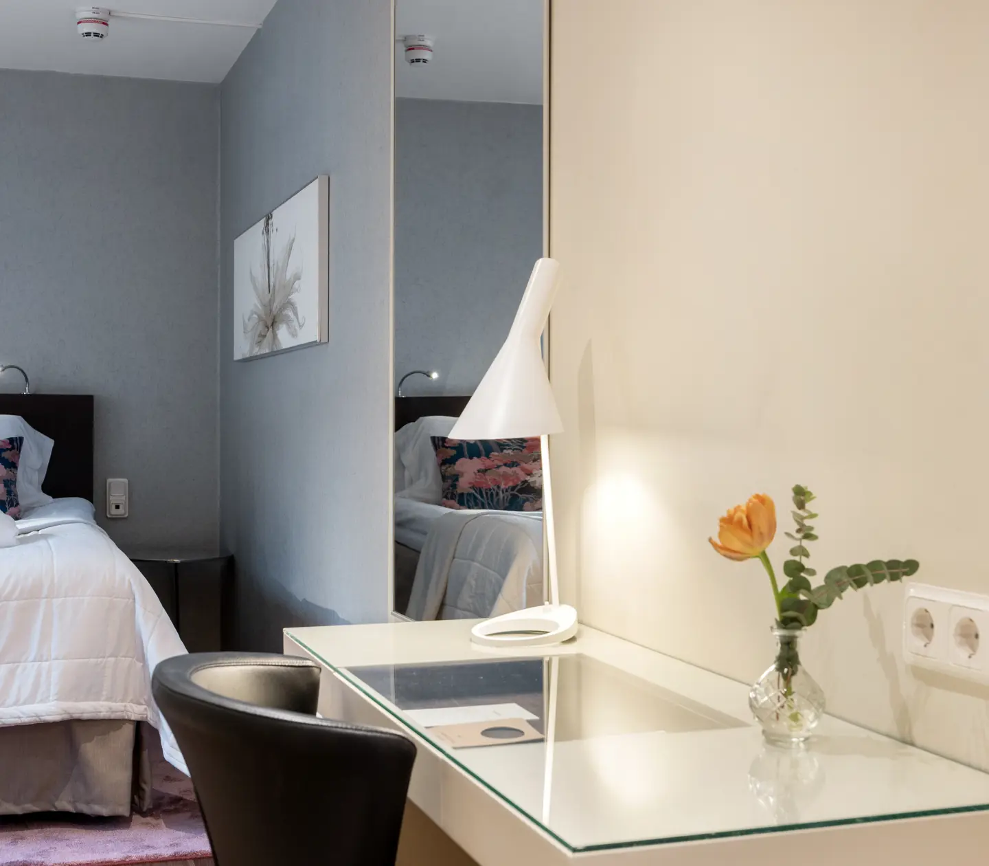 Mysigt hotellrum med dubbelsäng, tavla, spegel och skrivbord