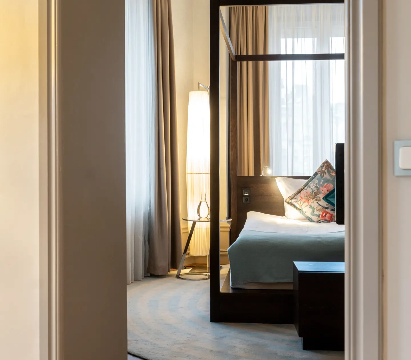 Mysig hotellsvit med dubbelsäng, golvlampa och tv