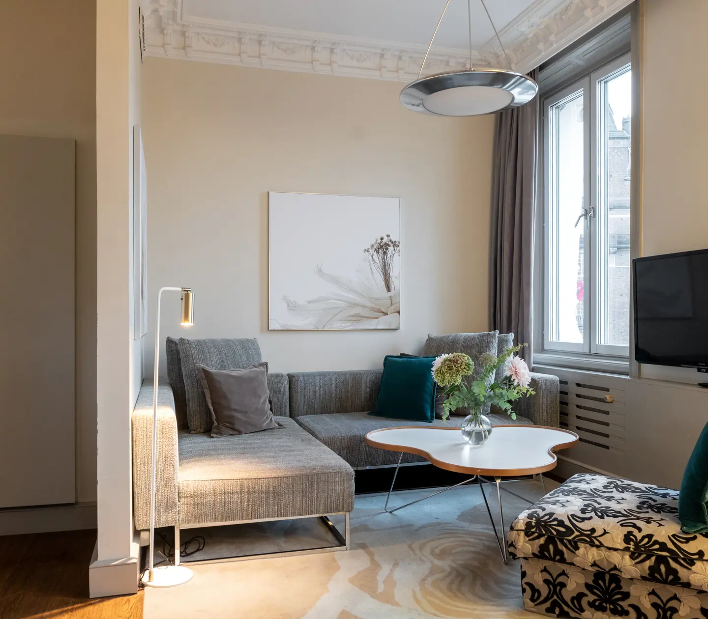 Ljus hotellsvit med garderober, soffa, tv och fönster