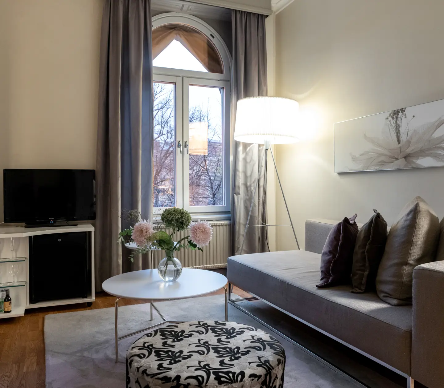 Hotellsvit soffa, tv, lampor och stort fönster
