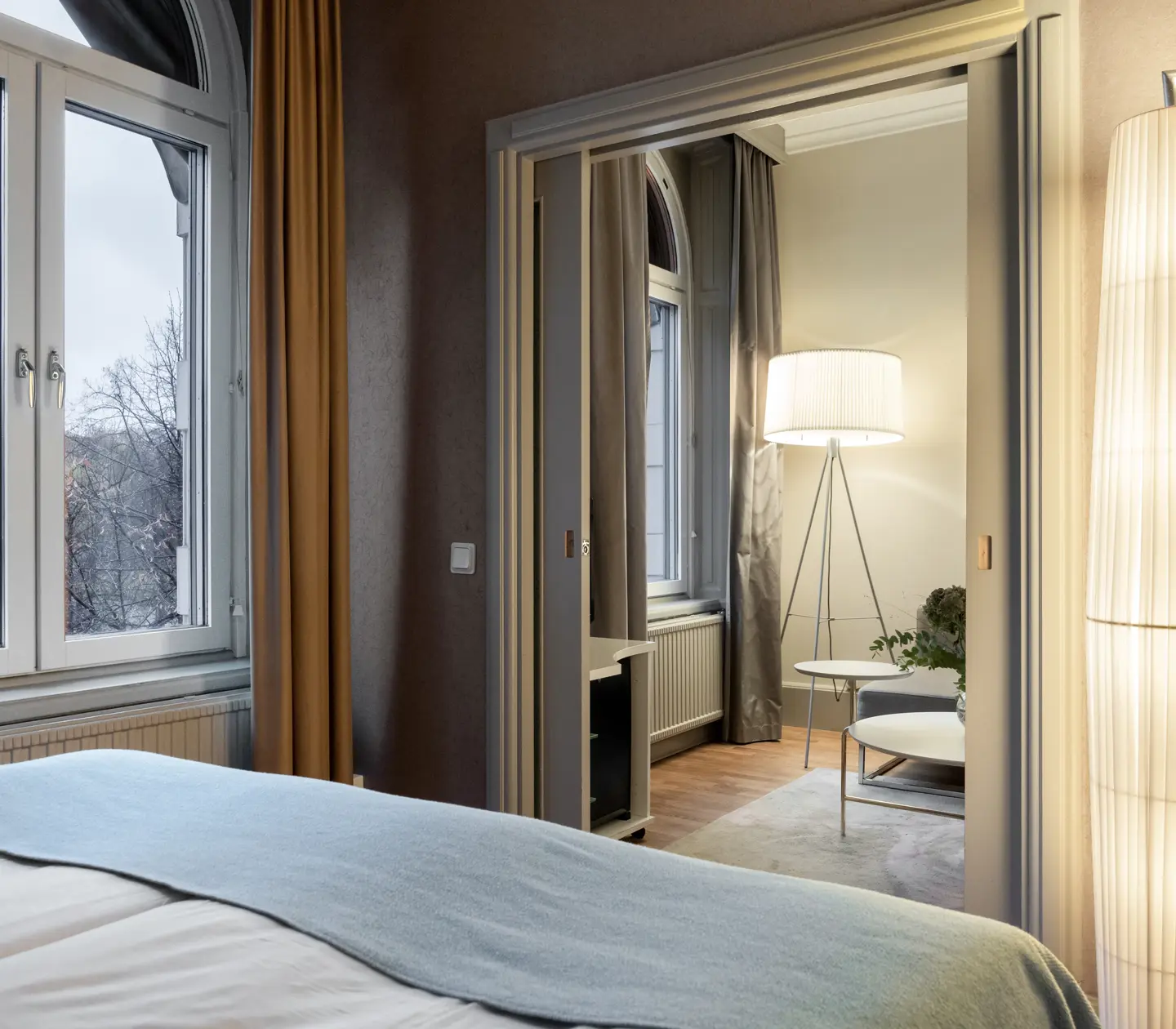 Mysigt hotellrum med dubbelsäng, fönster och dörr in till vardagsrum