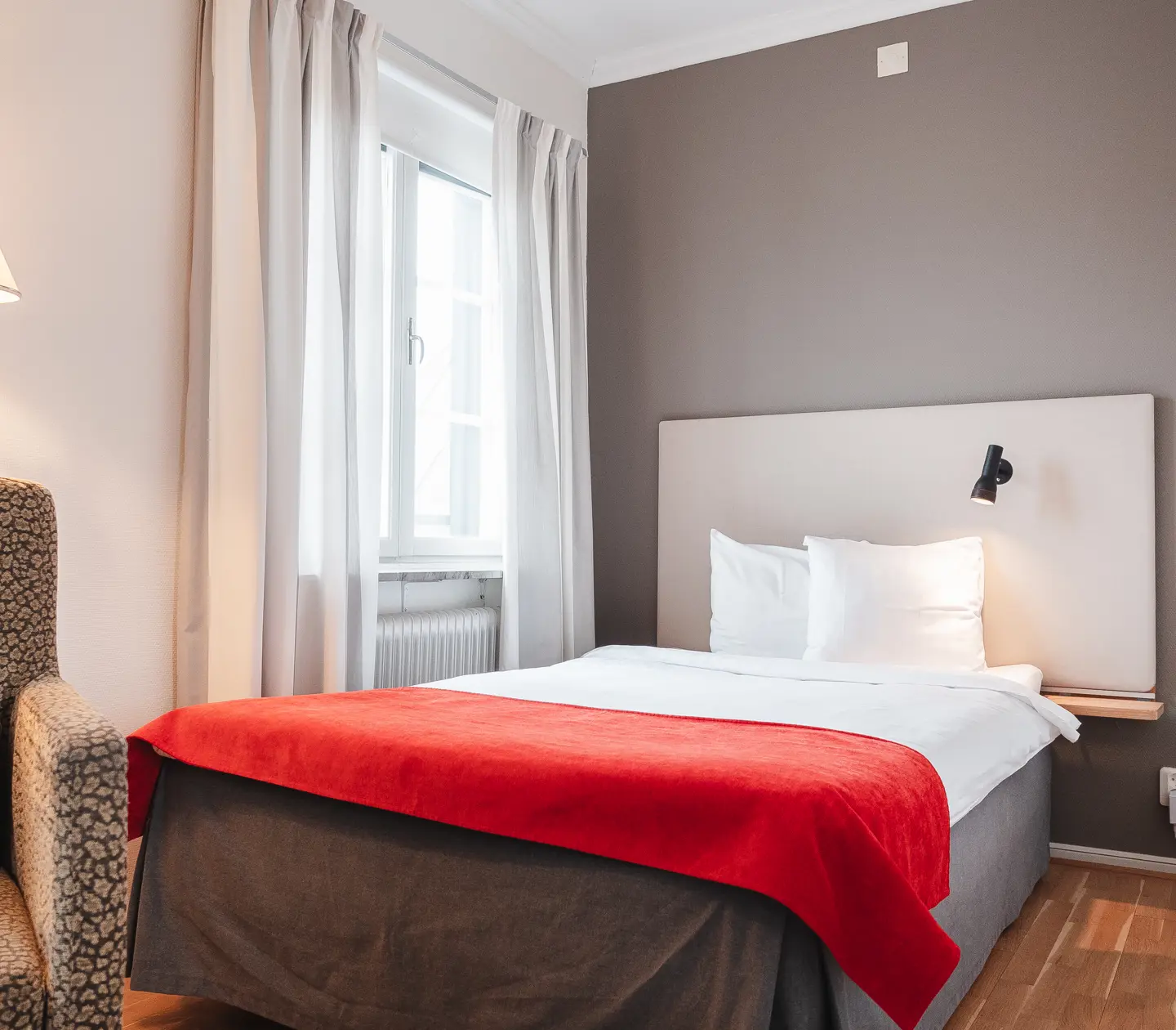 Mysigt hotellrum med säng, fåtölj och fönster